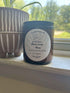 Black Coral Moss 7 oz coconut soy candle in dark glass jar beside brown striped pot on windowsill