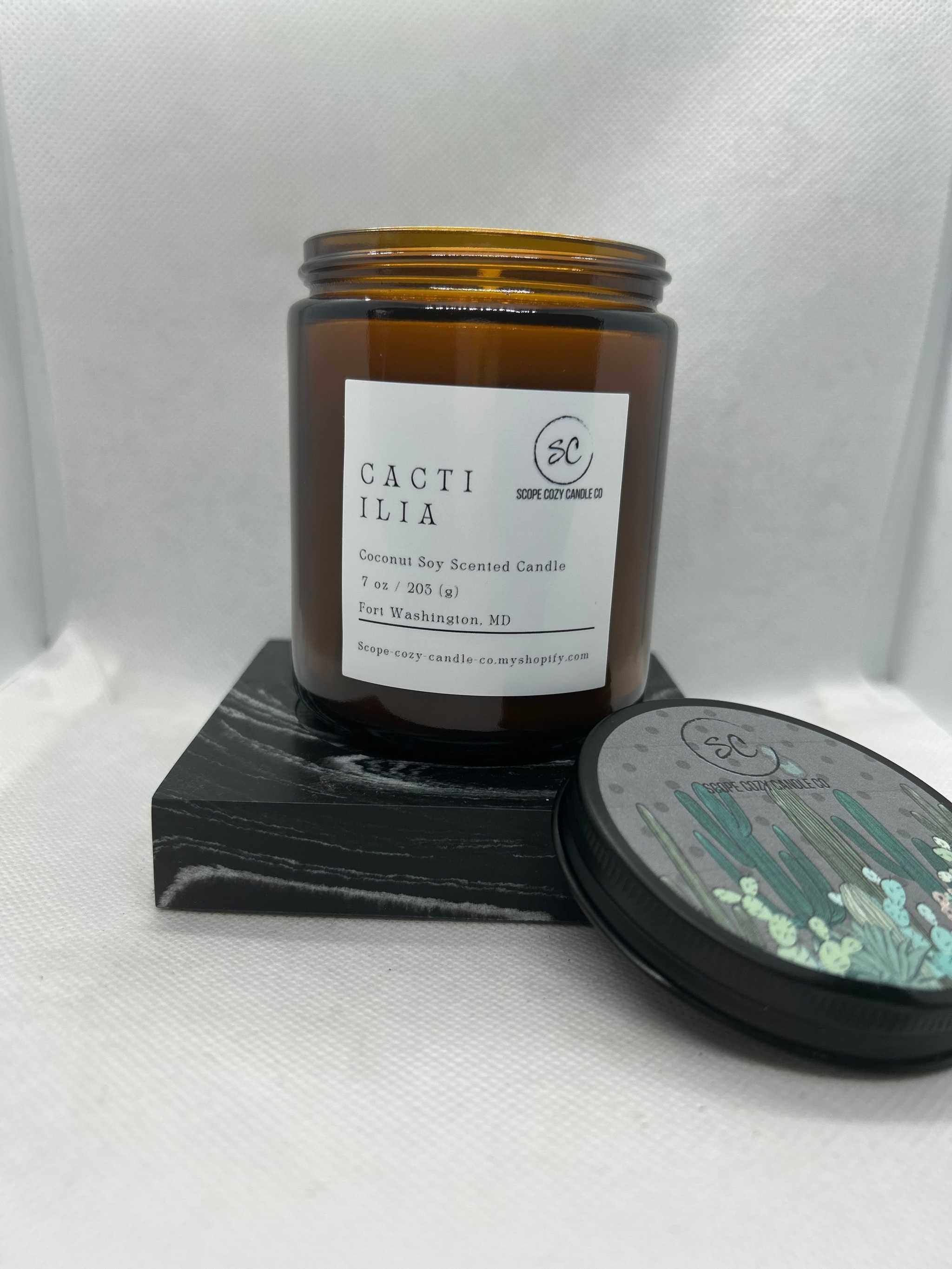 Cacti Ilia Coconut Soy Scented Candle 7oz in amber jar with black lid and wooden coaster