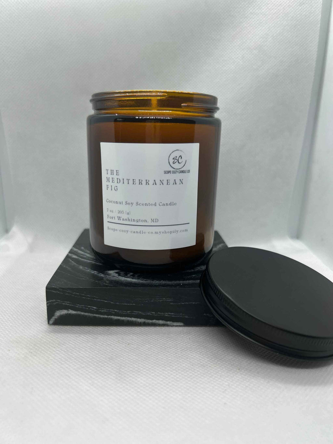 Mediterranean Fig Coconut Soy Candle 7 oz in amber jar with black lid on black wooden block