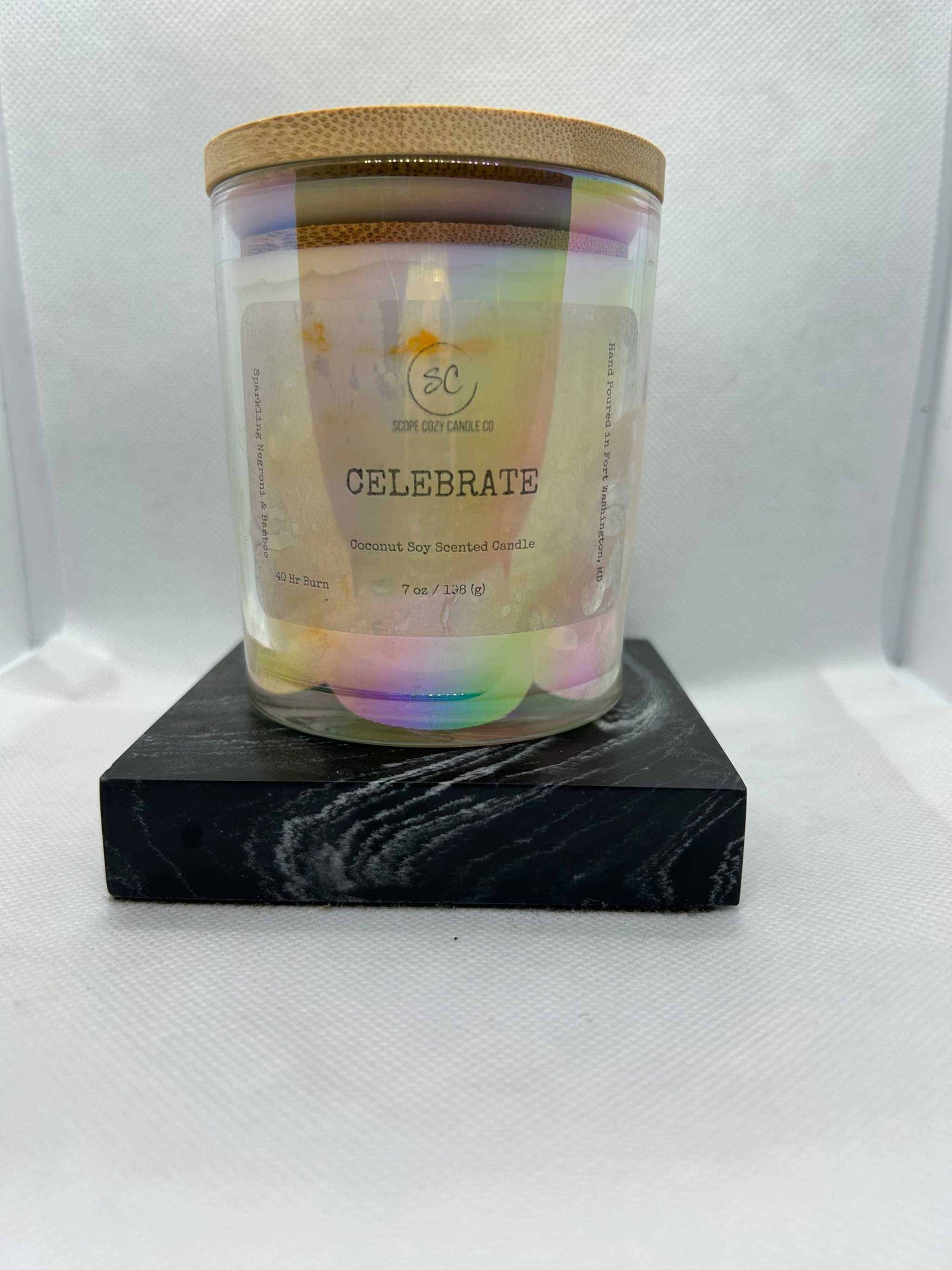Celebrate Coconut Soy Scented Candle 7oz with bamboo and coconut fragrance in a glass jar with wooden lid on black stand