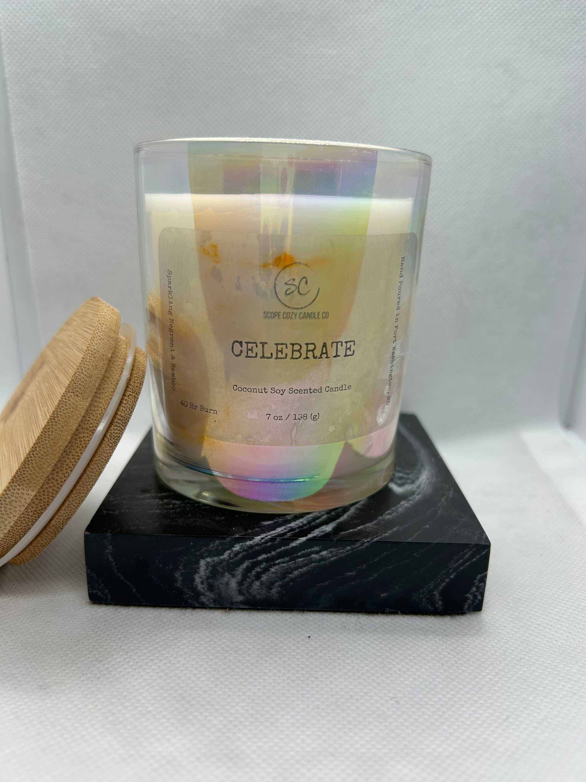 Celebrate Coconut Soy Scented Candle 7oz in iridescent glass with wooden lid on black marble base